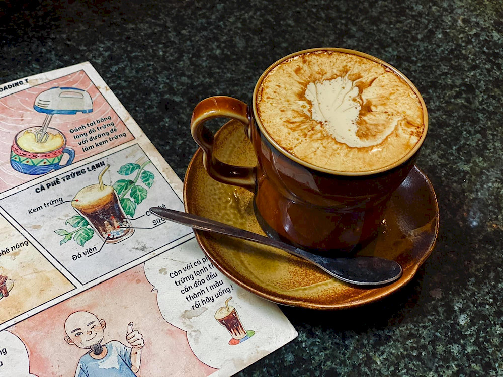 A rich creamy cup of egg coffee with delicate floral latte art at Loading T Café